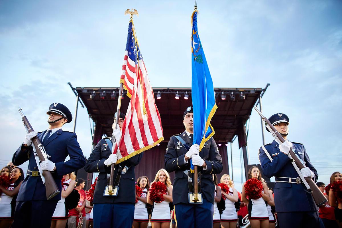A group of military uniformed men holding the Nevada flag and the US flag