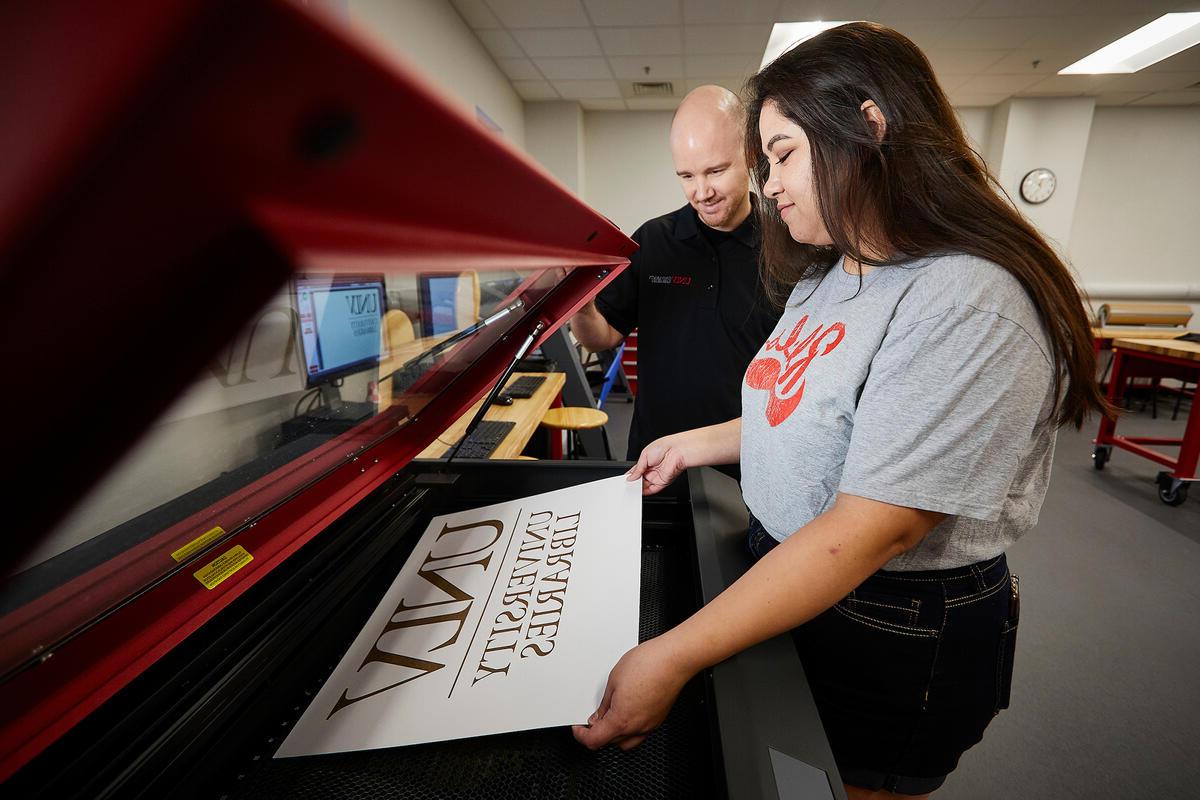 Student and advisor using an engraving machine to create a U.N.L.V. Libraries sign