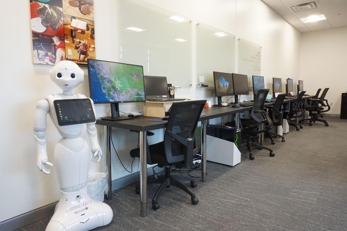 A room filled with computers, chairs, and a robot in the corner.