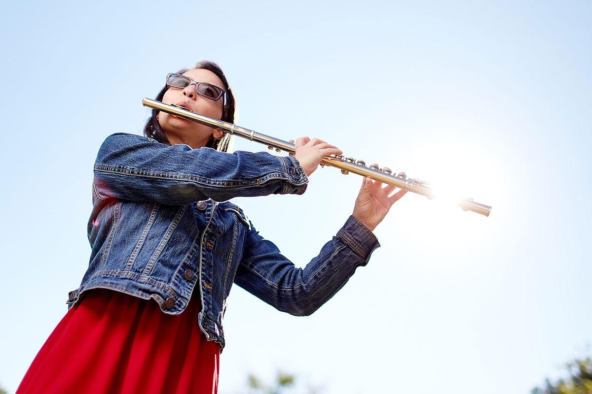 一个女人吹着笛子，阳光照在笛子的末端