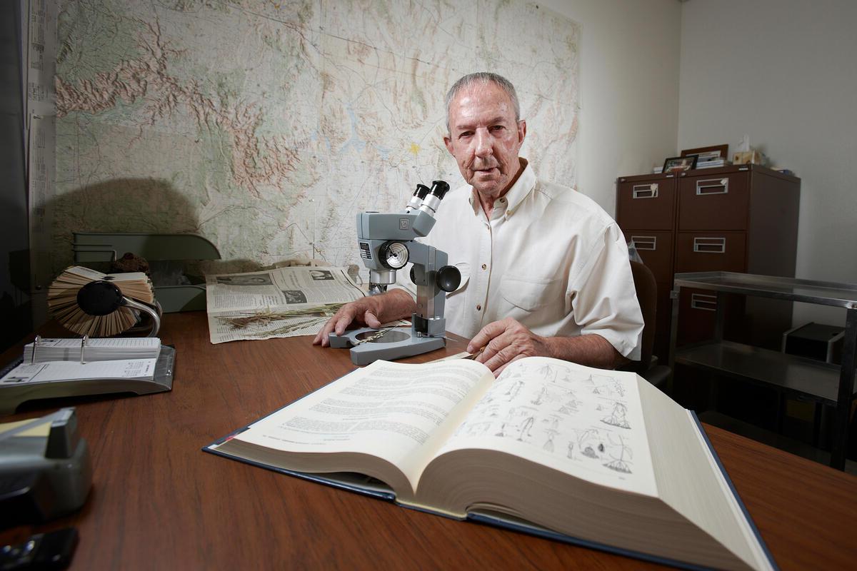 a man at a table with a microscope and open book