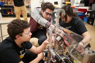 A UNLV student works with local high school students on a robot.