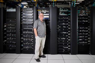 man standing in front of a row of black network servers