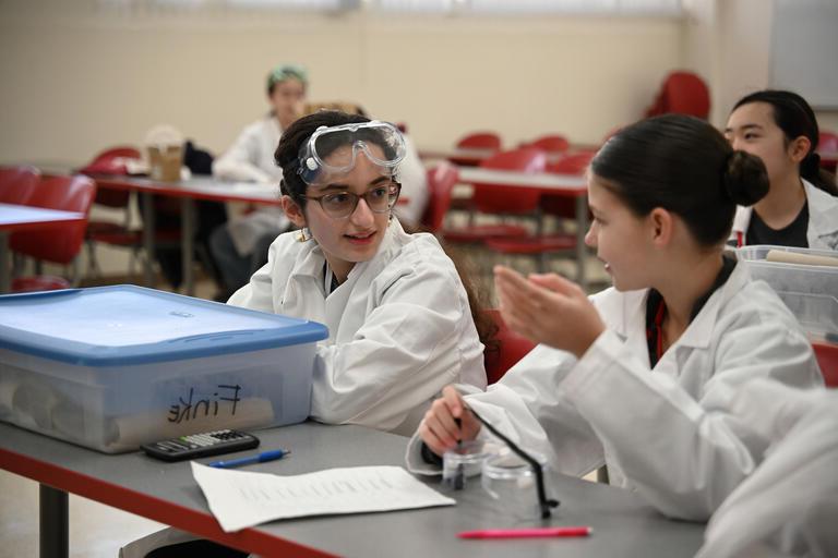 内华达州科学奥林匹克竞赛期间，两名年轻学生穿着实验服，戴着护目镜.