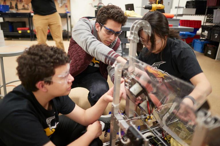一名加州大学洛杉矶分校的学生与当地高中生一起研究机器人.