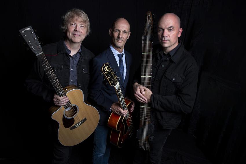Members of the California Guitar Trio, holding their instruments, look towards the camera in this promotional photo.